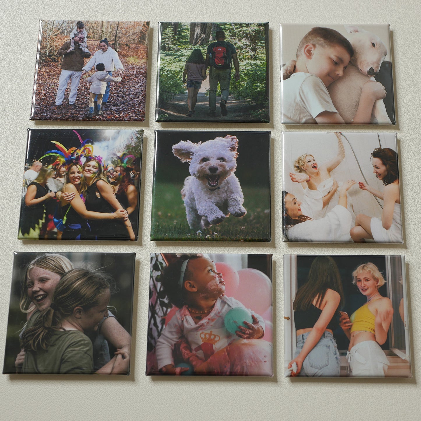 Nine 2×2 inch custom photo magnets arranged on a cream surface
