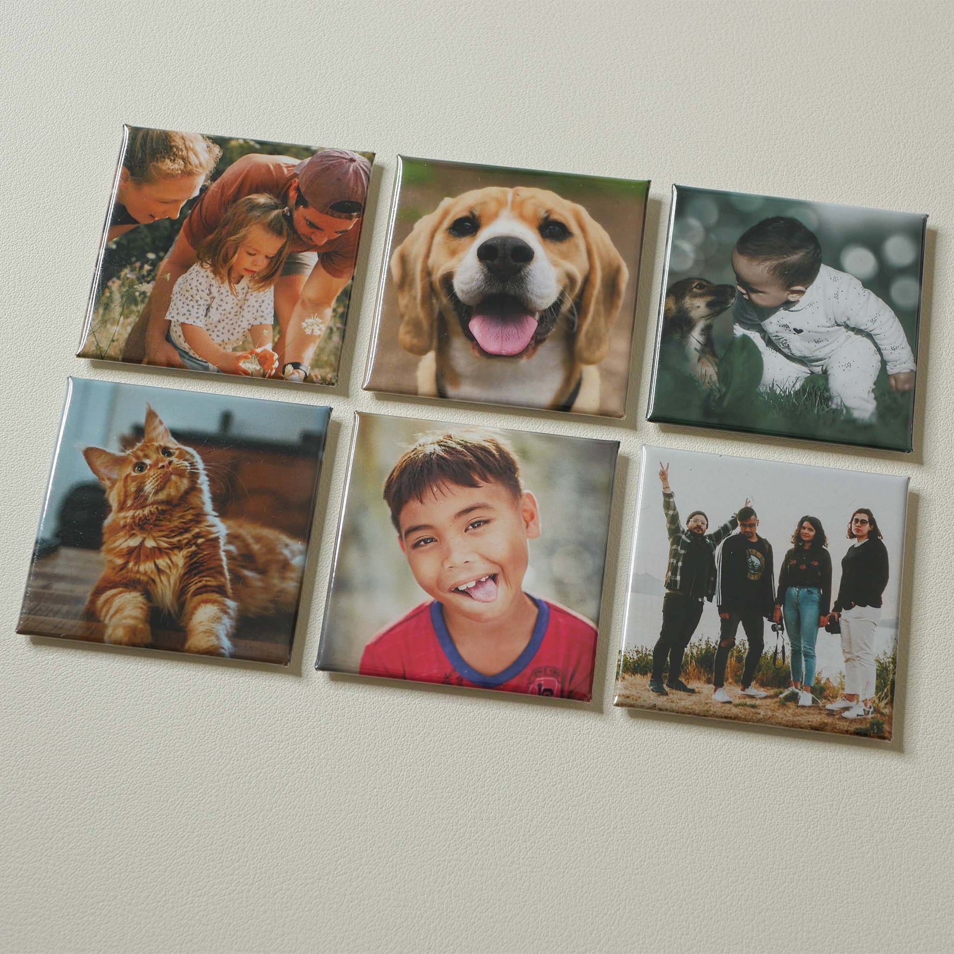 Six 2×2 inch custom photo magnets arranged on a cream surface