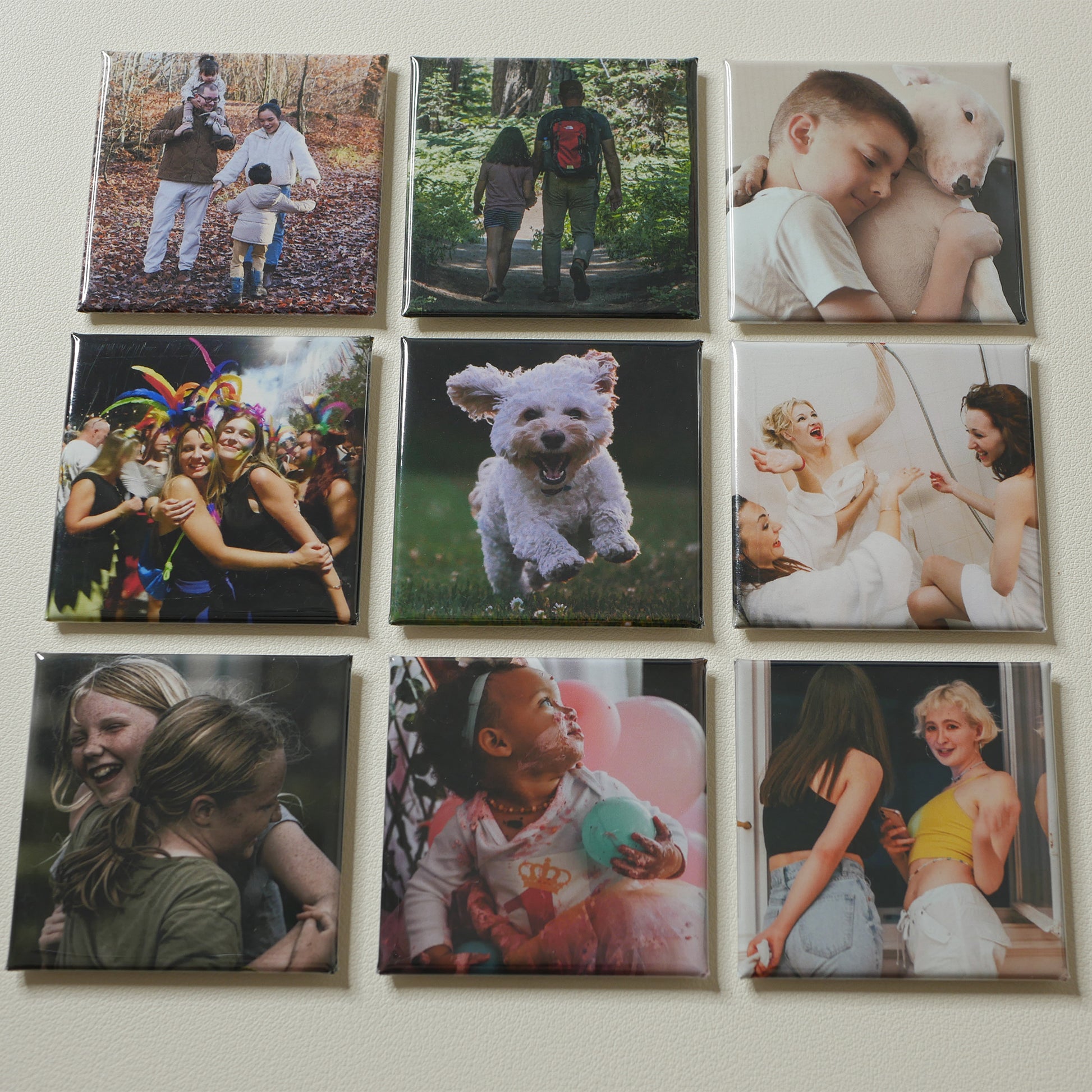 Nine 2×2 inch custom photo magnets arranged on a cream surface